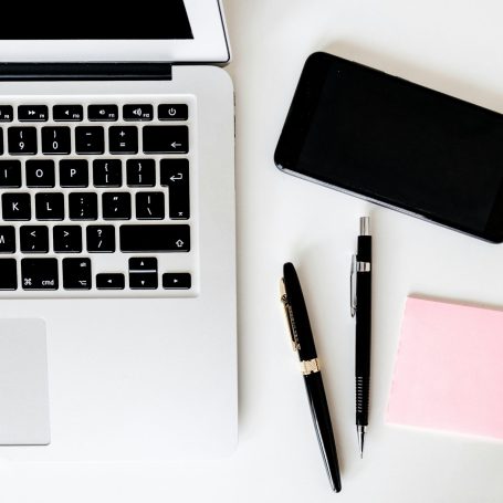 Laptop, Smartphone, Stift und Notizzettel auf Schreibtisch